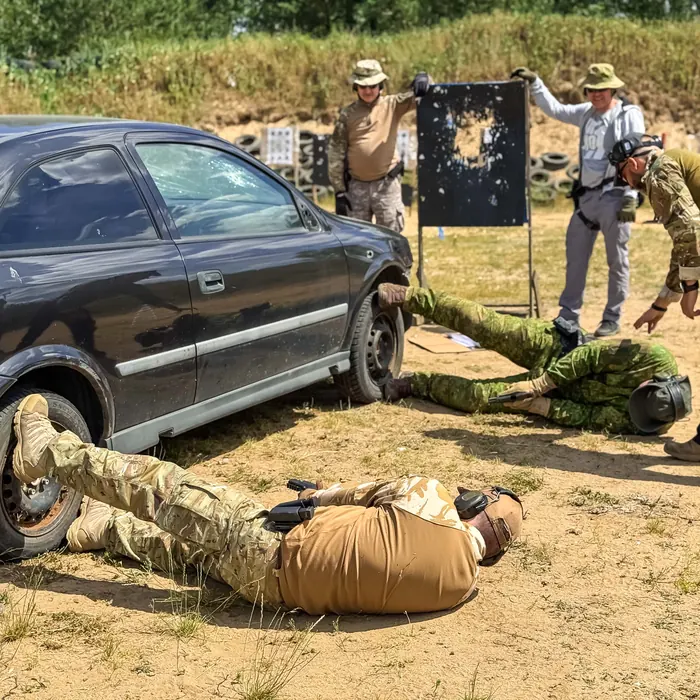 Kursanci ćwiczą wokół samochodu podczas obozu szkoleniowego